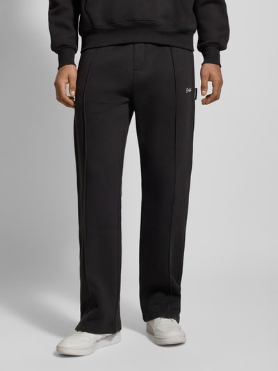Männermodel trägt Sweatpants mit elastischem Bund von PROHIBITED, Baumwoll-Mix, lockerer Schnitt, Label-Stitching, französische Eingrifftaschen, Farbe Schwarz, Ganzkörperansicht von vorne.