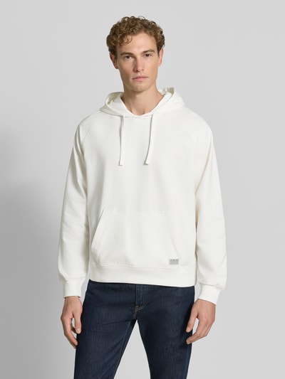 Męskki model nosi Relaxed Fit Hoodie aus Baumwoll-Mix mit Logo-Patch von GUESS, kolor biały, kieszeń kangurka, Ganzkörperansicht von vorne, mieszanka bawełny, naszywka z logo, kaptur z tunelem, długość tyłu 70 cm, długość rękawów 79 cm w rozmiarze M.