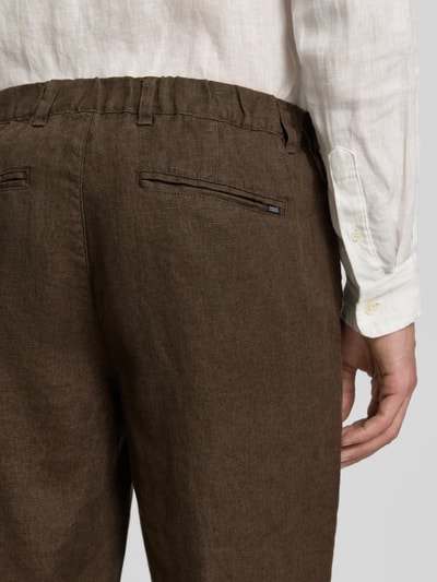 Männermodel trägt Leinenhose mit Eingrifftaschen Modell 'Pandrup' von Casual Friday, braun, Reine Leinen, Regular-Fit, Detailaufnahme Rückansicht, Bundweite bei Größe 32/32: 42 cm, Innenbeinlänge bei Größe 32/32: 83 cm.