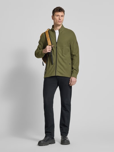 Männermodel trägt Sweatjacke mit Stehkragen und Reißverschluss von camel active in Olivgrün, Regular Fit, Ganzkörperansicht von vorne.