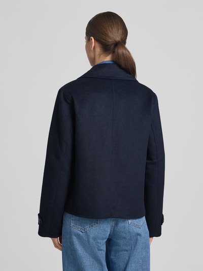 Frauenmodel trägt Kurzmantel mit Reverskragen und Eingrifftaschen von Stefanel in Dunkelblau, Material-Mix mit Leinen, Ganzkörperansicht Rückansicht.