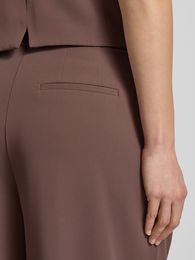 Frauenmodel trägt Wide Leg Stoffhose mit Raffungen von Christian Berg Cocktail, elastyczna mieszanka materiałów, brązowy kolor, marszczenia, wpuszczana kieszeń, długość wewnętrzna nogawki 82 cm, szerokość w rozmiarze 36: 38 cm, zapięcie na haftkę i zamek błyskawiczny, detailaufnahme tylnej części spodni.