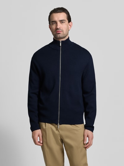 Männermodel trägt Relaxed Fit Strickjacke aus Viskose-Mix Modell 'TELLER' von SELECTED HOMME in Dunkelblau, Ganzkörperansicht von vorne. Unifarbene Feinstrick-Optik, Reißverschluss, Stehkragen, lange Ärmel mit geripptem Abschluss.