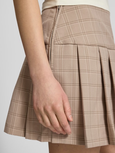 Kobiece modelka nosi Spódnica plisowana w wzór na całej powierzchni od Guess Jeans, mieszanka materiałów z dodatkiem wiskozy, linia A, spódnica mini, szerokość w rozmiarze S: 40 cm, długość wewnętrzna nogawki w rozmiarze S: 36 cm, beżowe odcienie, kratka, tekstura gładka, zbliżenie na dolną część ciała