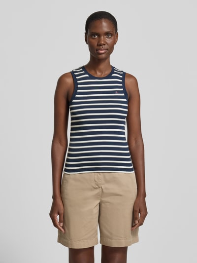 Vrouwenmodel draagt Slim Fit Tank Top uit puur katoen model 'SLIM CODY' van Tommy Hilfiger, look: effen met all-over motief, gestikt logo, ronde hals, brede bandjes, dames top, kleur: donkerblauw met lichtbeige strepen, materiaal: puur katoen. Ganzkörperansicht van voren.