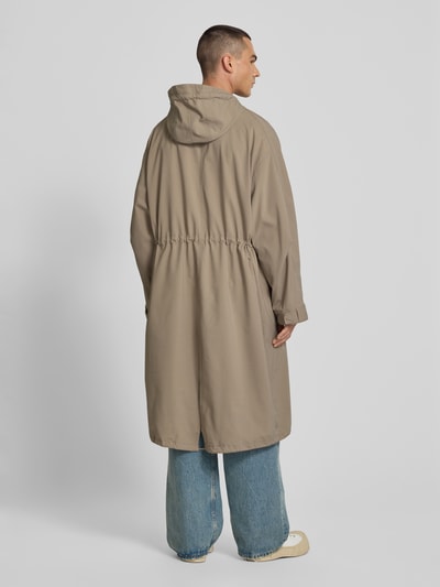 Mężczyzna nosi Parka mit Pattentaschen von MAISON KITSUNÉ, luźny krój, kaptur z tunelem, kieszenie z patką, plisa, zamek błyskawiczny, długość tyłu w rozmiarze M: 122 cm, szerokość ramion w rozmiarze M: 43 cm, długość rękawów w rozmiarze M: 69 cm, beżowe odcienie, gładka faktura, całkowity widok z tyłu