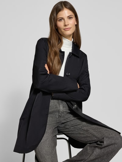 Frauenmodel trägt Mantel mit verdeckter Knopfleiste und Eingrifftaschen von Christian Berg Woman Selection in Schwarz, Ganzkörperansicht von vorne. Rückenlänge 87 cm, Schulterbreite 40 cm, Brustweite 54 cm, Ärmellänge 62 cm, Kentkragen, gerader Schnitt.