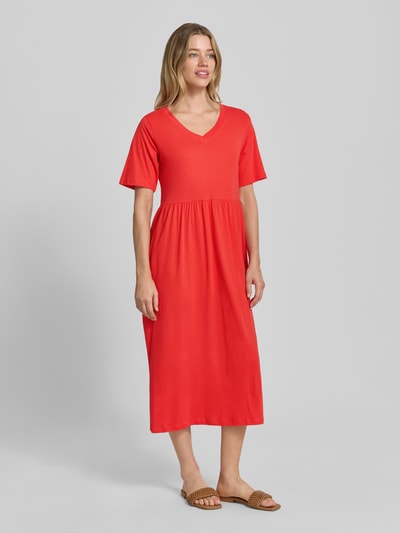 Frauenmodel trägt Midikleid mit Smok-Details Modell 'DERBY' von Soyaconcept in Rot, A-Linie, reine Baumwolle, Ganzkörperansicht von vorne.