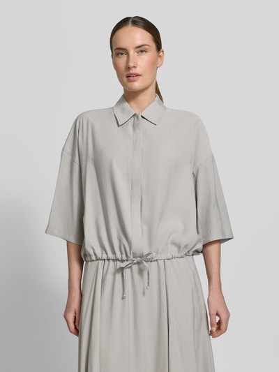 Modelka kobieca nosi Boxy Fit Bluse aus Modal-Mix Modell 'LAINAY' od Drykorn, szara bluzka damska z kołnierzem, 3/4 rękawem i troczkiem, długość tyłu 54 cm, długość rękawa 27 cm, widok na górną część ciała z przodu.