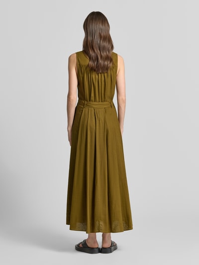 Frauenmodel trägt Maxikleid aus Leinen-Viskose-Mix mit Gürtel von Stefanel in Olive, Wickel-Optik, taillierter Schnitt, Ganzkörperansicht Rückansicht.