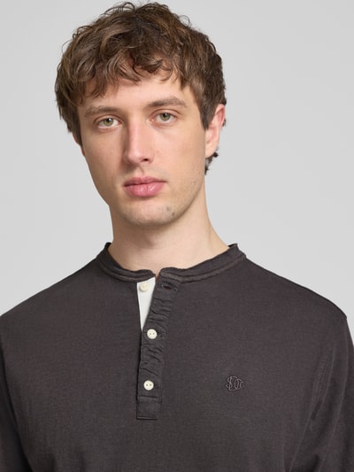 Männermodel trägt T-Shirt mit kurzer Knopfleiste von Superdry aus Leinen-Baumwoll-Mix, Regular-Fit, Polokragen, Logo-Stitching, Nahaufnahme Oberkörper.