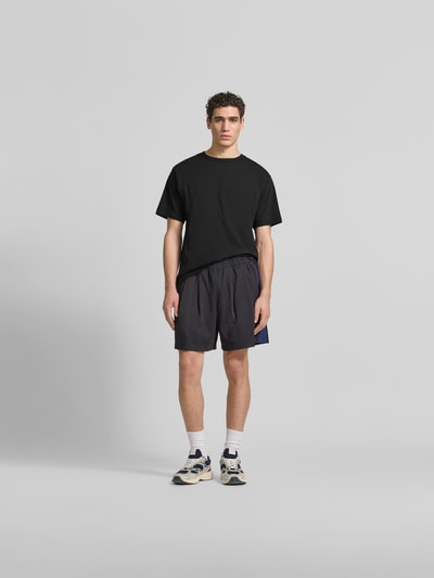 Männermodel trägt T-Shirt mit Rundhalsausschnitt von Kenzo aus reiner Baumwolle, Relaxed-Fit, Logo-Stitching, kurzärmelig, schwarz, Ganzkörperansicht von vorne.