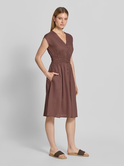 Frauenmodel trägt Knielanges Kleid aus Leinen-Mix mit Knopfleiste von Christian Berg Woman Selection in Braun, taillierter Schnitt, V-Ausschnitt, Kappärmel, Smok-Details, glatte Textur, Knielänge, Rückenlänge bei Größe 36: 44 cm, Brustweite: 44 cm, Ganzkörperansicht von vorne.