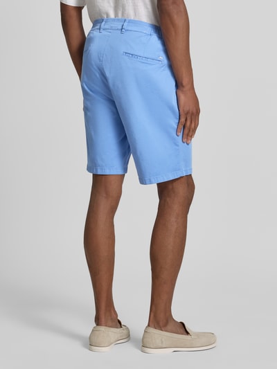 Männermodel trägt Relaxed Fit Bermuda aus Baumwoll-Mix Modell 'TINO' von Brax in Hellblau, unifarben, mit Gürtelschlaufen und Taschen, Ganzkörperansicht Rückansicht.