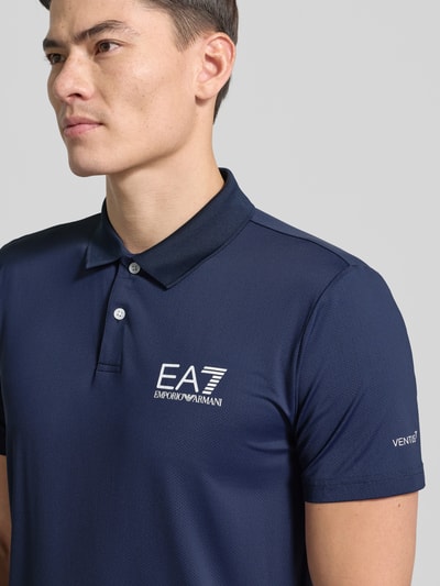 Mannelijk model draagt Regular Fit Poloshirt met Logo van EA7 Emporio Armani in marineblauw, materiaal-mix met stretch, logo op borst, nahaufnahme bovenlichaam.