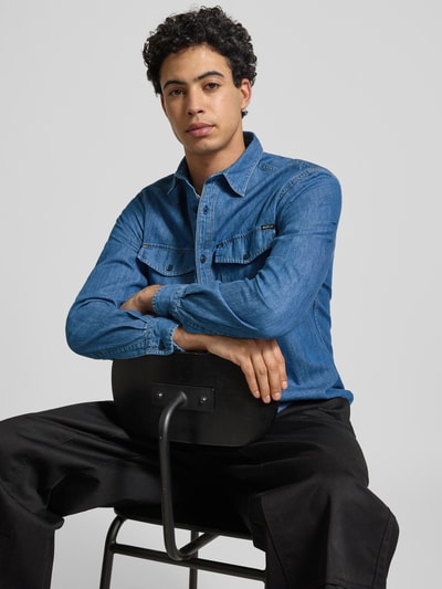 Männermodel trägt Regular Fit Jeanshemd aus reiner Baumwolle von Replay in Blau mit durchgehender Knopfleiste, Nahaufnahme Oberkörper.