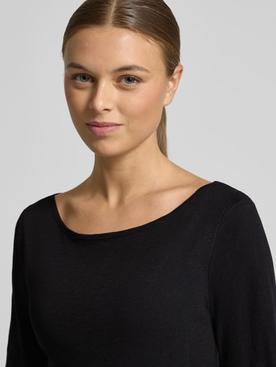 Vrouwenmodel draagt Longsleeve uit biologische katoen van MARC O’POLO, smal gesneden, zwarte slub jersey, detailopname bovenlichaam.