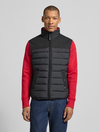 Männermodel draagt Regular Fit Steppweste aus wasserdichtem Material van Tom Tailor, look: effen, ritssluiting, opstaande kraag, materiaalverwerking: gerecycled materiaal, waterdicht, ademend, waterafstotend, ganzkörperansicht van voren.