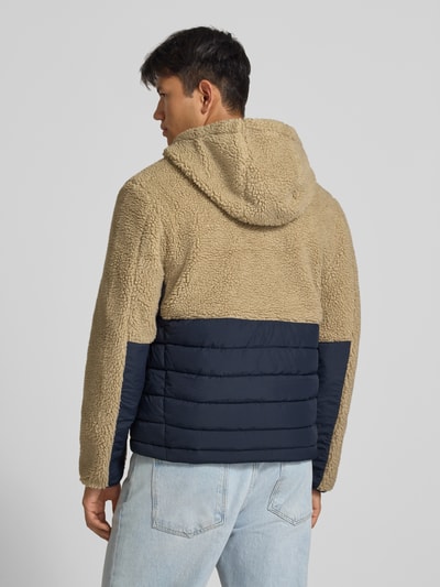 Męski model nosi Regular Fit Jacke mit Teddyfell Modell 'Borg' od Superdry, beżowy i granatowy, tekstura pluszu, widok całej sylwetki z tyłu. Długość pleców w rozmiarze M: 64 cm, szerokość ramion w rozmiarze M: 45 cm, szerokość klatki piersiowej w rozmiarze M: 55 cm, długość rękawa w rozmiarze M: 68 cm.