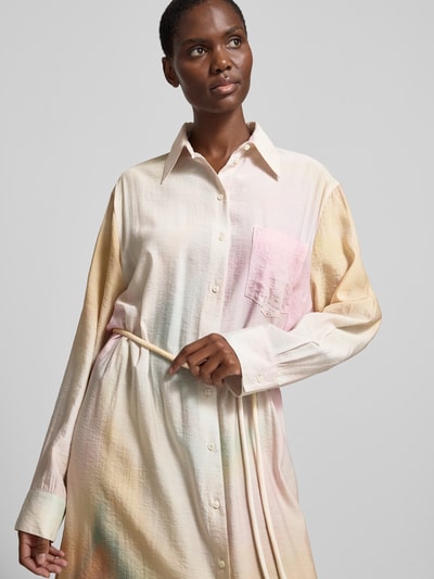 Frauenmodel trägt Hemdblusenkleid aus Viskose-Mix von Nanushka in sanften Pastellfarben mit durchgehender Knopfleiste, Hemdblusenkragen, Langärmelig, Gerade Passform, Nahaufnahme Oberkörper.