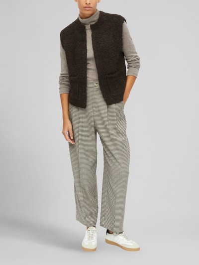 Frauenmodel trägt Regular Fit Strickweste mit Woll-Anteil von s.Oliver RED LABEL in Dunkelbraun, kombiniert mit grauen Karohosen, Ganzkörperansicht von vorne.