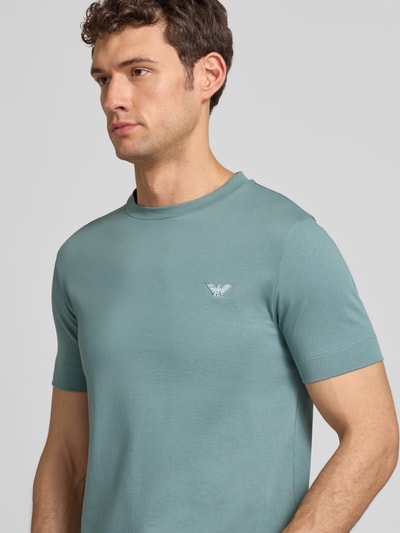 Männermodel trägt T-Shirt mit Label-Stitching und Rundhalsausschnitt von Emporio Armani aus reiner Baumwolle, Slim-Fit, Nahaufnahme Oberkörper.