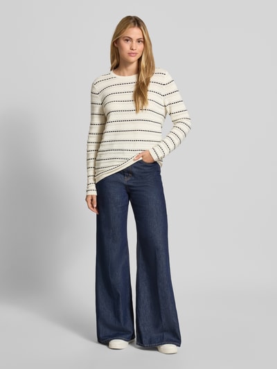Frauenmodel trägt Regular Fit Longsleeve aus reiner Baumwolle von Christian Berg Woman, Rundhalsausschnitt, Strick-Optik, creme mit dunklen Streifen, kombiniert mit weiter Jeans, Ganzkörperansicht von vorne.