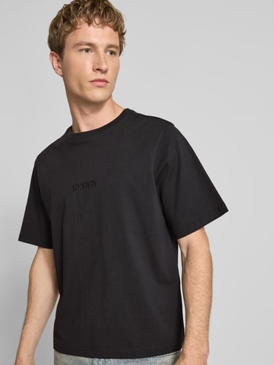 Männermodel trägt T-Shirt mit Rundhalsausschnitt und Logo-Stitching von REVIEW in Schwarz aus reiner Baumwolle, regular Fit, Nahaufnahme Oberkörper.