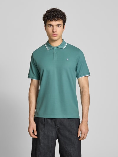 Männermodel trägt Regular Fit Poloshirt mit Strukturmuster Modell 'AUSTIN' von Jack & Jones, Material-Mix, Stitching, Knopfleiste, Farbe Grün, Ganzkörperansicht von vorne. Rückenlänge bei Größe M: 69 cm.