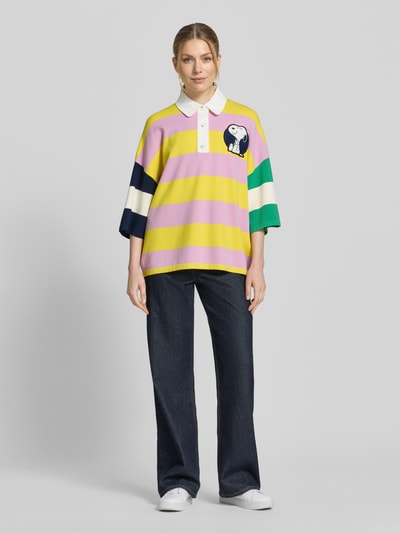 Kobiece model prezentuje wielokolorową koszulkę polo Oversized Poloshirt aus Viskose-Mix Modell 'JICE STRIPED EMBO' od Essentiel Antwerp z mieszanki wiskozy, wzór w paski, aplikacja z motywem, detal z tekstem, prążkowane wykończenia, drobny splot, kołnierzyk polo, krój oversized, rękaw o dł. 3/4, krótkie zapięcie na guziki; pełny widok z przodu.