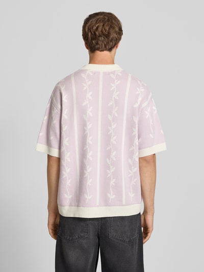 Männermodel trägt Relaxed-Fit Poloshirt mit Logo-Stitchings Modell 'Kinsale' von Pegador aus reiner Baumwolle in zarten Pastelltönen, Rückenlänge bei Größe M 69 cm, Gerippter Polokragen, kurze Knopfleiste, Kontrastkante, Ganzkörperansicht Rückansicht.
