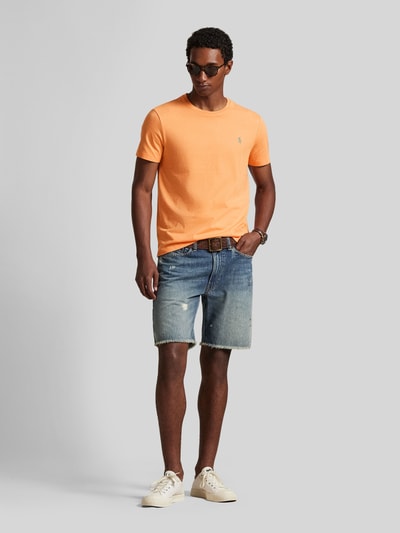 Männermodel trägt Regular Fit T-Shirt aus reiner Baumwolle von Polo Ralph Lauren in Orange, unifarben, Logo-Stitching, Ganzkörperansicht von vorne.