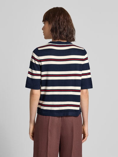 Frauenmodel trägt Boxy Fit Strickshirt aus Viskose-Mix Modell 'VMSILJE' von VERO MODA, Streifenmuster in Dunkelblau, Weiß und Rot, Ganzkörperansicht Rückansicht.