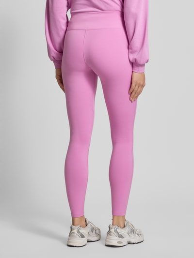 Frauenmodel trägt Leggings mit Logo-Print Modell 'One' von NIKE TRAINING in Pink, Material-Mix mit Stretch-Anteil, Slim-Fit, elastischer Bund, Ganzkörperansicht Rückansicht.