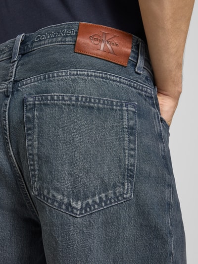 Mężczyznamodel nosi Loose Fit Jeansshorts aus reiner Baumwolle od Calvin Klein Jeans, dżins w odcieniach niebieskiego, skórzana naszywka z logo, 5-kieszeniowy fason, bawełna, detal z szlufkami, zapięcie na guzik i ukryty zamek, widok na tylne kieszenie, detalaufnahme tył.