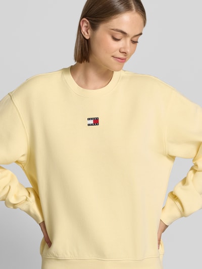 Vrouwenmodel draagt lichtgeel regular fit sweatshirt van katoenmix Regular Fit Sweatshirt aus Baumwoll-Mix van Tommy Jeans, Nahaufnahme bovenlichaam. Dames sweatshirt van Tommy Jeans