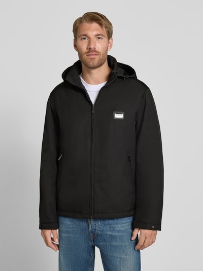 Männermodel trägt schwarze Regular Fit Jacke mit Stehkragen von Emporio Armani, Zweiwege-Reißverschluss, Logo-Applikation, Ganzkörperansicht von vorne.