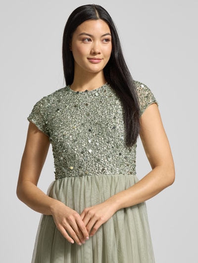 Kobiece modelka nosi Sukienka wieczorowa z cekinowym obszyciem od Lace & Beads, siateczka, taliowany krój, długość do ziemi, jednokolorowa, okrągły dekolt, zapięcie na haftkę i wszyty zamek, nieprzezroczysta halka, rozmiar S: długość tyłu 147 cm, szerokość biustu 39 cm, długość rękawa 12 cm, kolorystyka zielona, faktura błyszcząca góra, perspektywa: zbliżenie na górną część ciała.