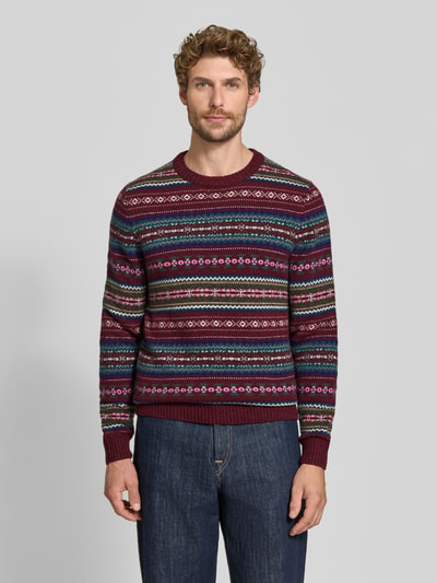 Männermodel trägt Slim Fit Strickpullover aus Baumwoll-Mix mit Rundhalsausschnitt von MCNEAL, rot gemustert, Ganzkörperansicht von vorne. Herren Strickpullover, gerippte Blende, langärmlig, gerippte Abschlüsse.