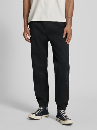 Männermodel trägt Straight Fit Jeans aus reiner Baumwolle von Tommy Jeans in dunkler Denim-Optik, elastischer Bundabschluss, 5-Pocket-Design, Ganzkörperansicht von vorne.