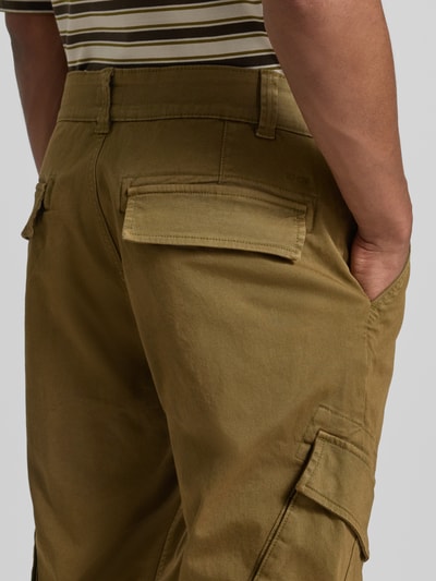 Männermodel trägt Straight Fit Cargohose aus Baumwoll-Mix von MCNEAL, Olivgrün, mehrere Taschen, elastischer Material-Mix, Nahaufnahme Rückansicht. Bundweite 45 cm, Innenbeinlänge 80 cm, Knopf- und Reißverschluss.