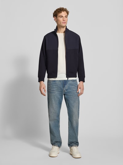 Männermodel trägt Regular Fit Jacke aus Baumwoll-Mix Modell 'FELPA' von Armani Exchange in Dunkelblau, Ganzkörperansicht von vorne. Elastischer Baumwoll-Mix, Stehkragen, Zweiwege-Reißverschluss, elastische Abschlüsse, Rückenlänge 66 cm, Ärmellänge 63 cm.