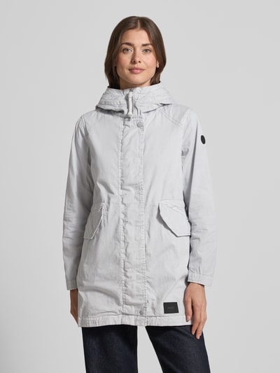 Modelka nosi Parka mit Pattentaschen Modell 'NIKA' od khujo z bawełny, krój regular fit, kaptur, kieszenie z patką, kolor jasnoszary, długość tyłu w rozmiarze S 81 cm, szerokość ramion w rozmiarze S 40 cm, szerokość klatki piersiowej w rozmiarze S 51 cm, długość rękawów w rozmiarze S 60 cm, widok całej sylwetki z przodu.