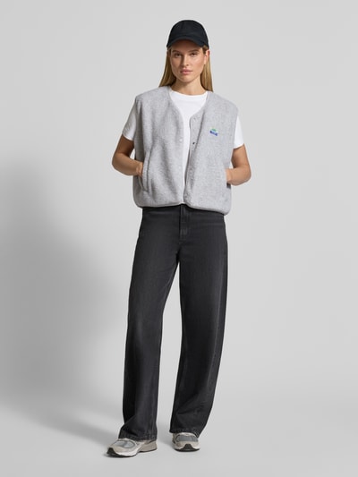 Frauenmodel trägt Weste mit Rundhalsausschnitt Modell 'HOKTOWN' von American Vintage, grau, Teddyfell, entspannter Schnitt, Eingrifftaschen, Ganzkörperansicht von vorne.