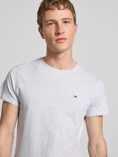 Männermodel trägt Regular Fit T-Shirt aus reiner Baumwolle von Tommy Jeans, Optik: Unifarben, Logo-Stitching, Nahaufnahme Oberkörper.