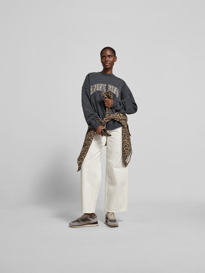Frauenmodel trägt Oversized Sweatshirt aus Baumwolle von Anine Bing in Dunkelgrau mit Rundhalsausschnitt und elastischen Abschlüssen, Ganzkörperansicht von vorne.