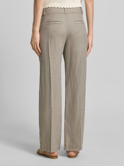 Kobiece modelka nosi Leinenhose mit Eingrifftaschen od Christian Berg Woman, len, krój regular fit, kieszenie, beżowy, tekstura lnu, widok całej sylwetki z tyłu.