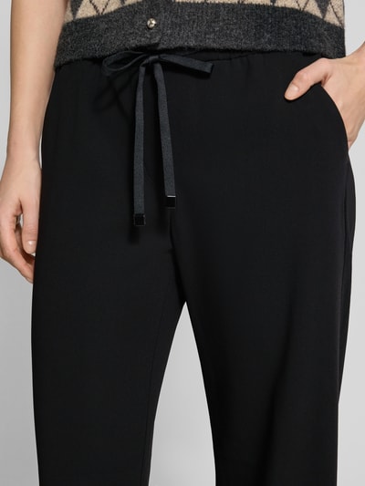 Frauenmodel trägt Stoffhose mit elastischem Bund Modell 'Christy' von MAC, Material-Mix mit Stretch-Anteil, lockerer Schnitt, Tunnelzug, Eingrifftaschen, Gesäßtasche, Nahaufnahme Oberkörper.