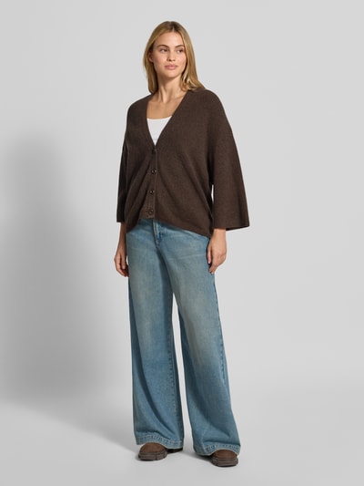 Kobiece model prezentuje Oversized Cardigan aus Baumwoll-Anteil Modell 'DAMSVILLE' von American Vintage, elastyczna mieszanka materiałów, krój oversized fit, imitacja dzianiny, listwa guzikowa, dekolt w serek, długość tyłu w rozmiarze XS/S: 63 cm, długość rękawów w rozmiarze XS/S: 35 cm, widok całej sylwetki z przodu.