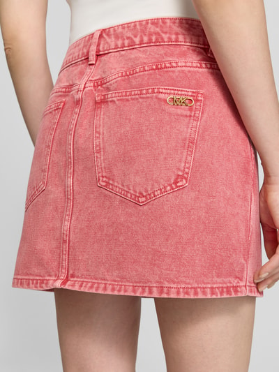 Frauenmodel trägt Mini-Jeansrock mit Eingrifftaschen von MICHAEL Michael Kors in Rosa, reine Baumwolle, gerader Schnitt, Nahaufnahme Rückansicht.